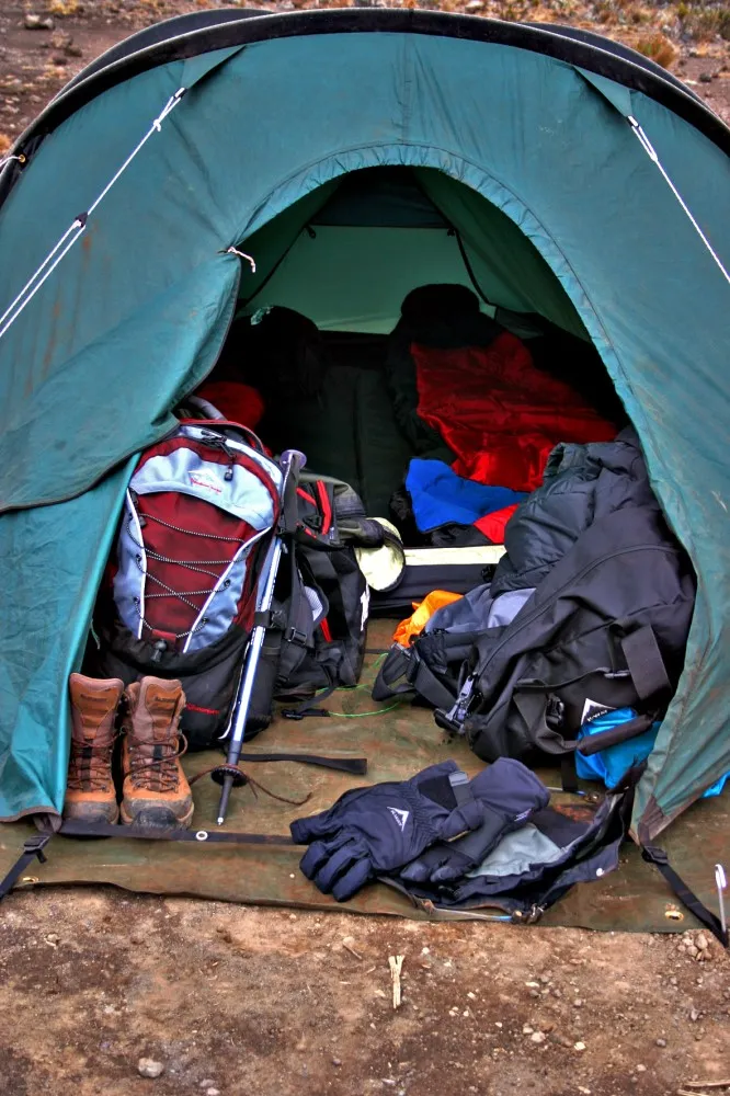 Kilimanjaro hiking gear including boots, trekking poles and equipment inside a mountain tent