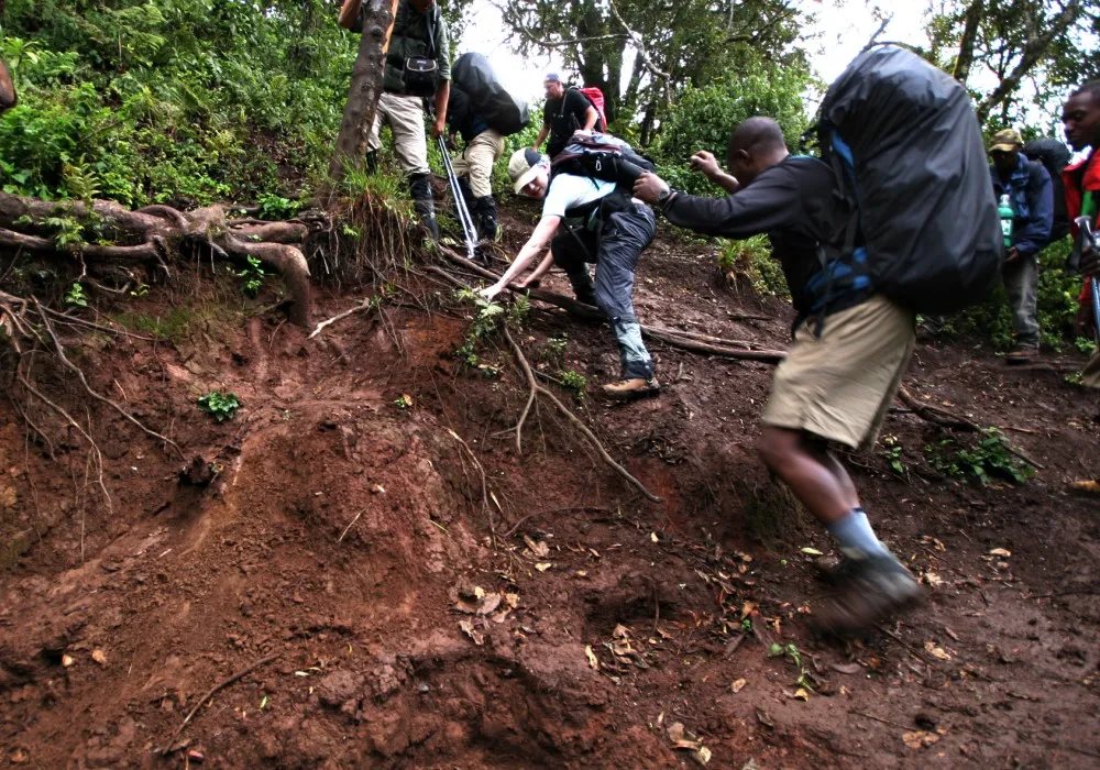Kilimanjaro guide helping a hiker negotiate difficult terrain