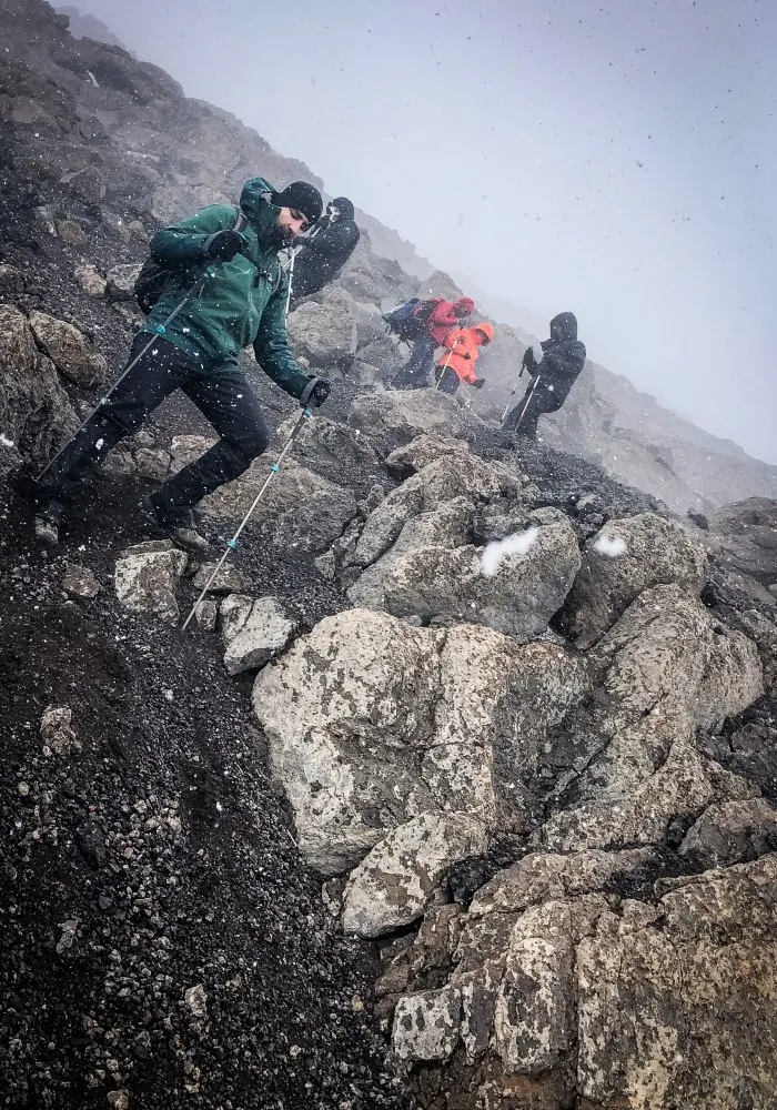 Hikers descending Mount Kilimanjaro in wet and rainy conditions