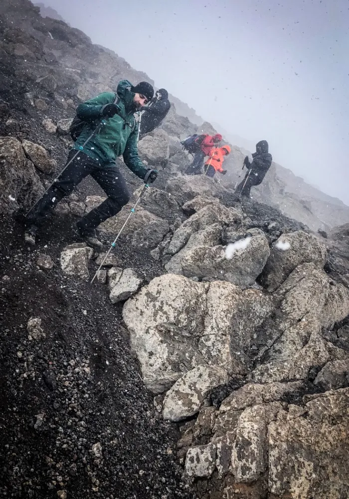 Hikers descending Mount Kilimanjaro in wet and rainy conditions