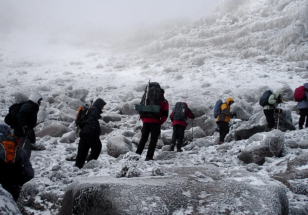 Hikers walking through snow high on Mount Kilimanjaro