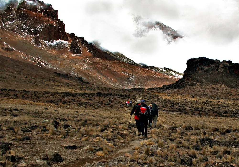 Kilimanjaro hikers walking across mountain terrain during a long trekking day