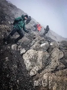 Hikers climbing steep rocky terrain on Mount Kilimanjaro
